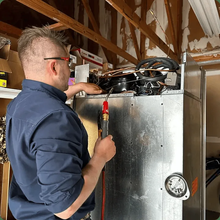 Refrigeration technician brazing a sealed system with a torch